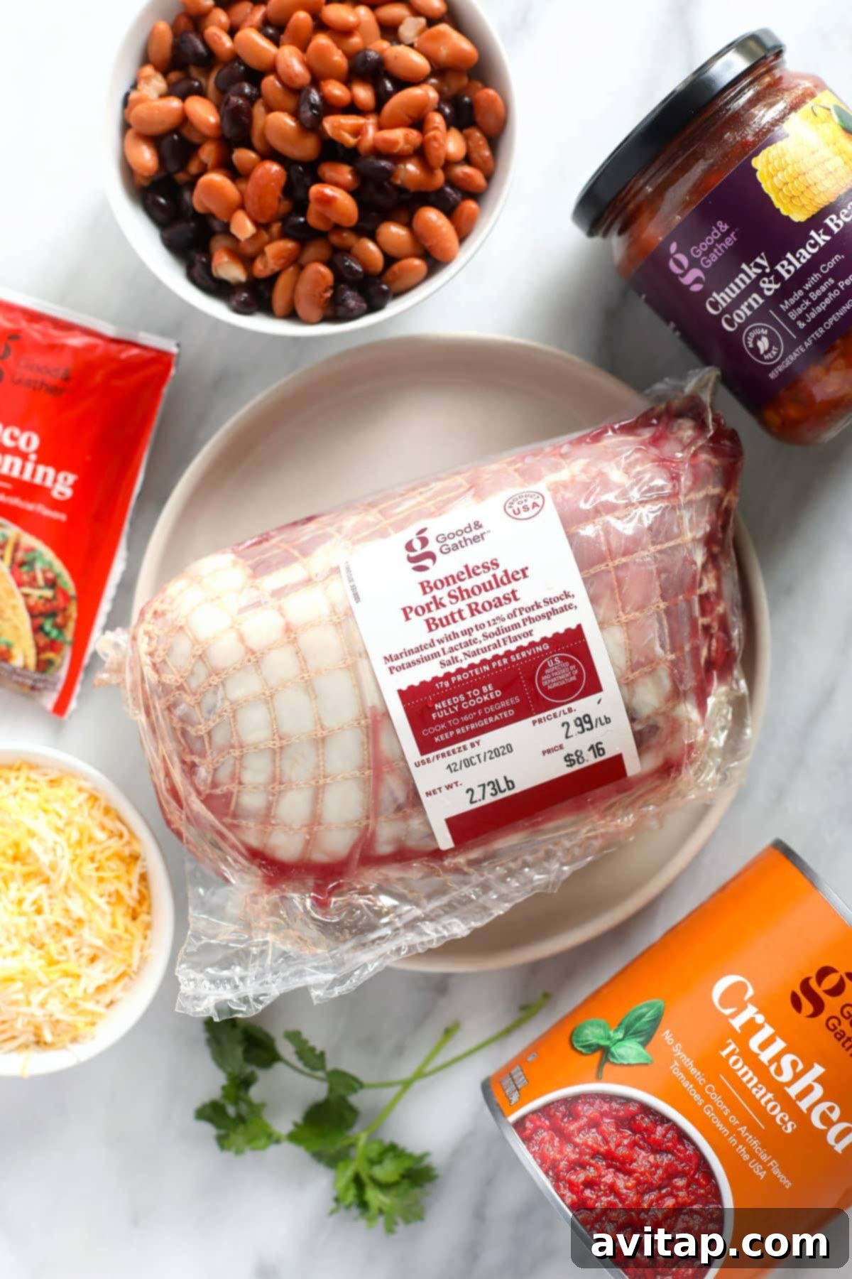 Key ingredients laid out for Instant Pot Pork Chili: pork shoulder, taco seasoning, cheese, crushed tomatoes, salsa, and assorted beans.