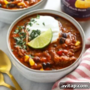 Two bowls of Instant Pot Pork Chili, richly topped with sour cream or Greek yogurt and fresh herbs.