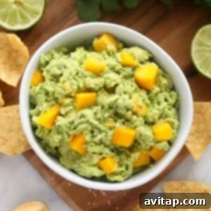 Tropical Mango Guacamole 2 A bowl of vibrant mango guacamole, garnished with fresh cilantro and a lime wedge, ready to be served with crispy tortilla chips.