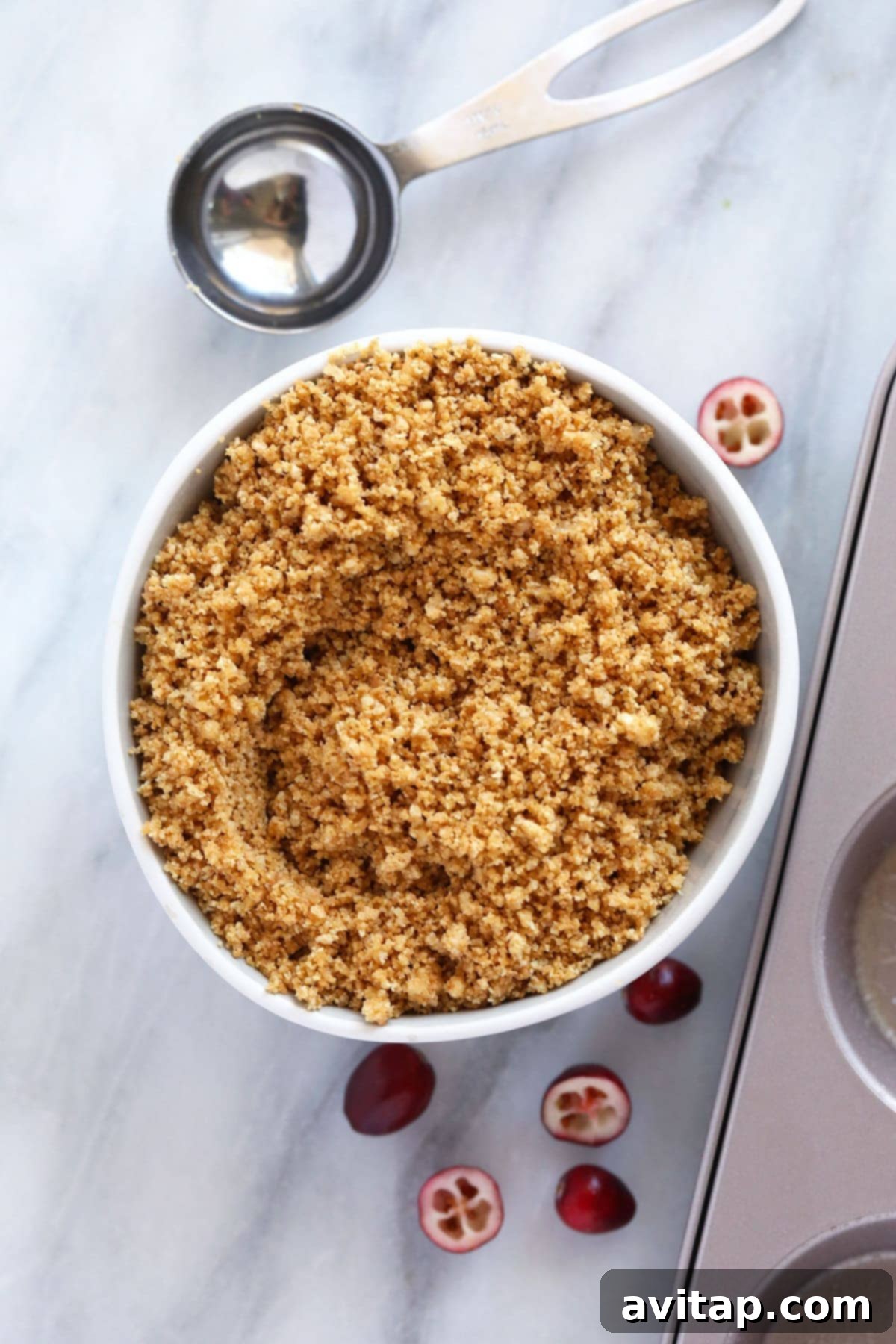 A bowl of graham cracker crumble, ready to be pressed into the crust for cranberry cheesecake bites.