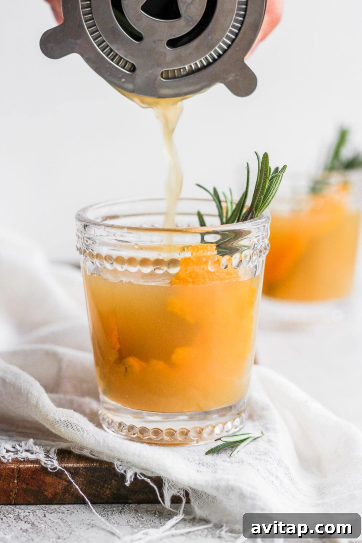 A festive Apple Cider Cocktail garnished with fresh rosemary and an orange slice, perfect for holiday celebrations.