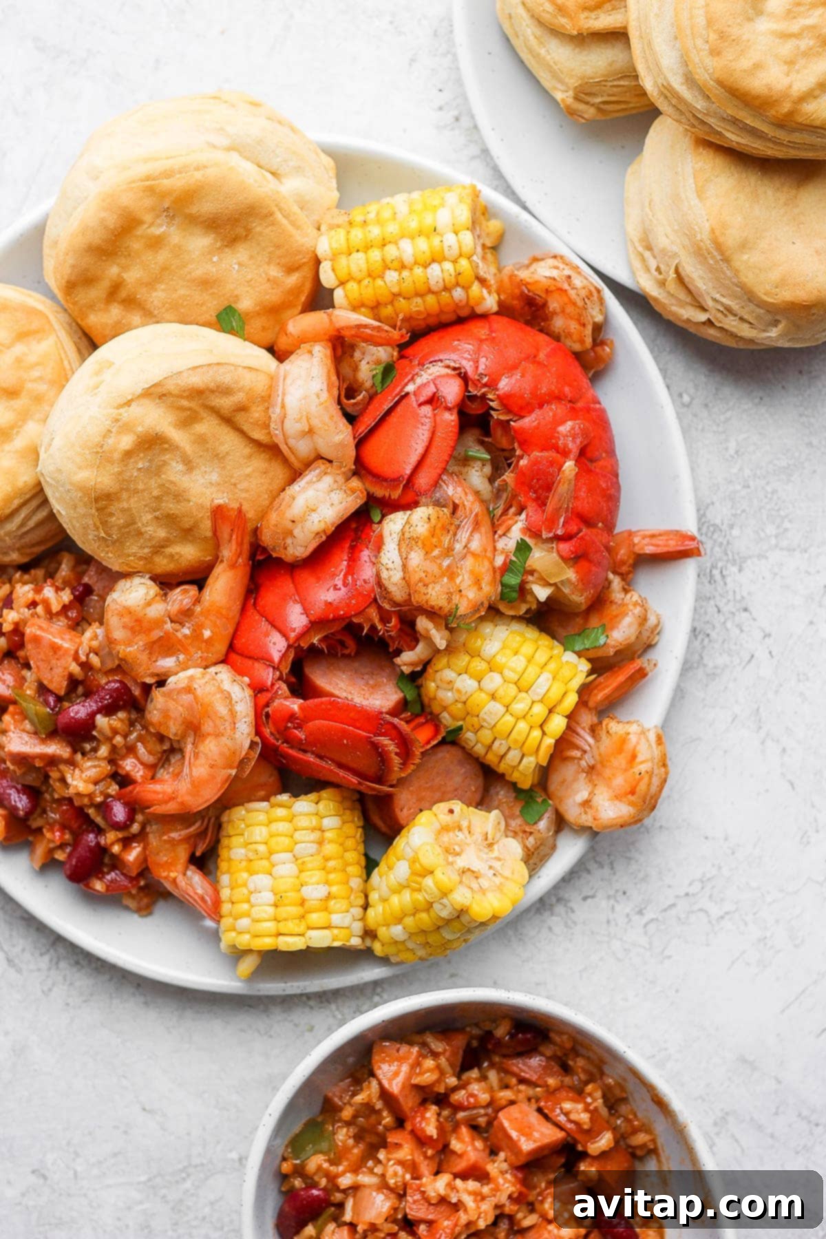 A vibrant, easy seafood boil served generously on a platter with rice, beans, and biscuits, highlighting lobster, shrimp, sausage, and corn.