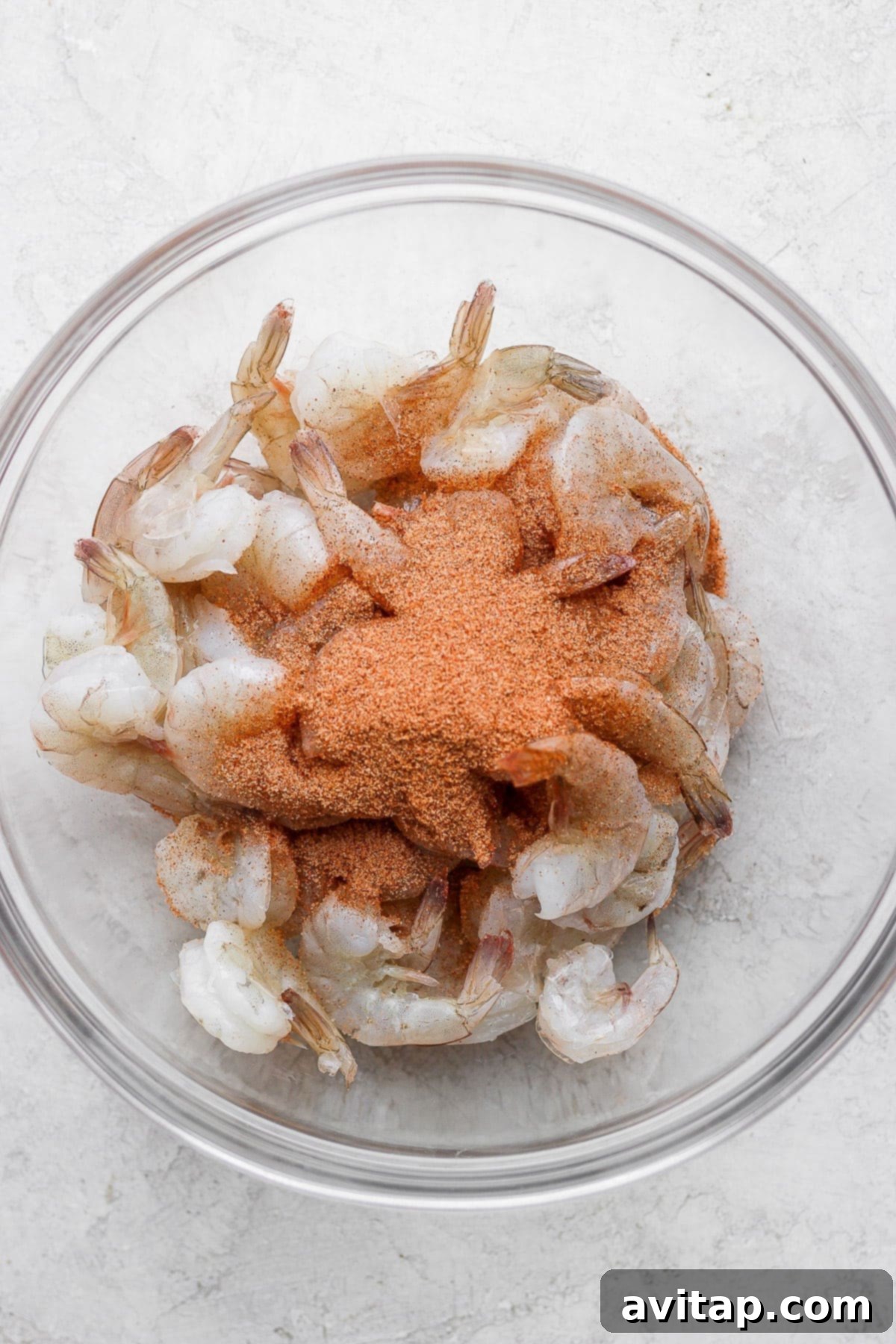 Raw jumbo shrimp generously coated in a rich Cajun seasoning blend, ready for the seafood boil.