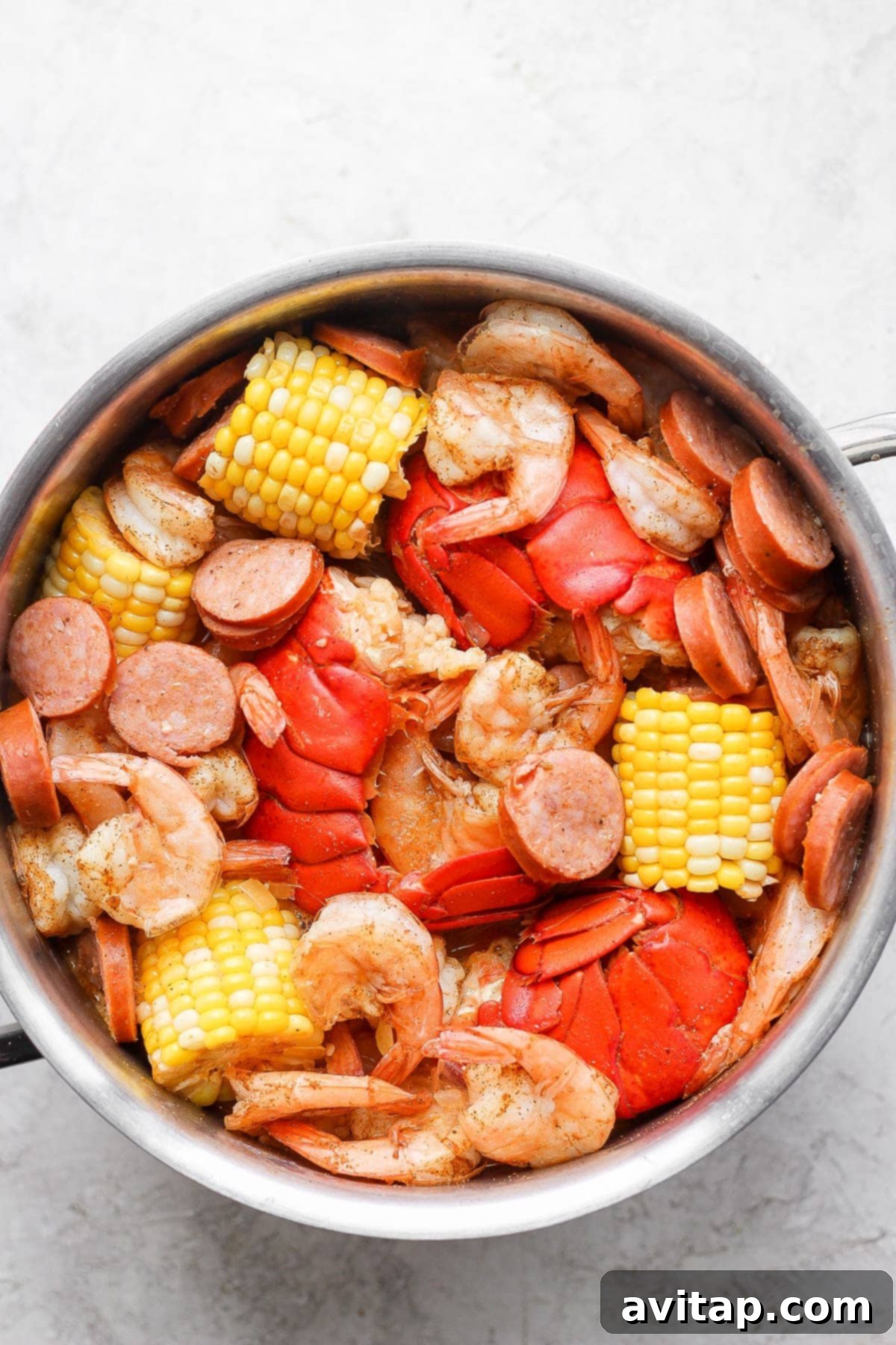 The complete easy seafood boil, cooked to perfection and brimming with lobster, shrimp, sausage, corn, and potatoes in a large stockpot.