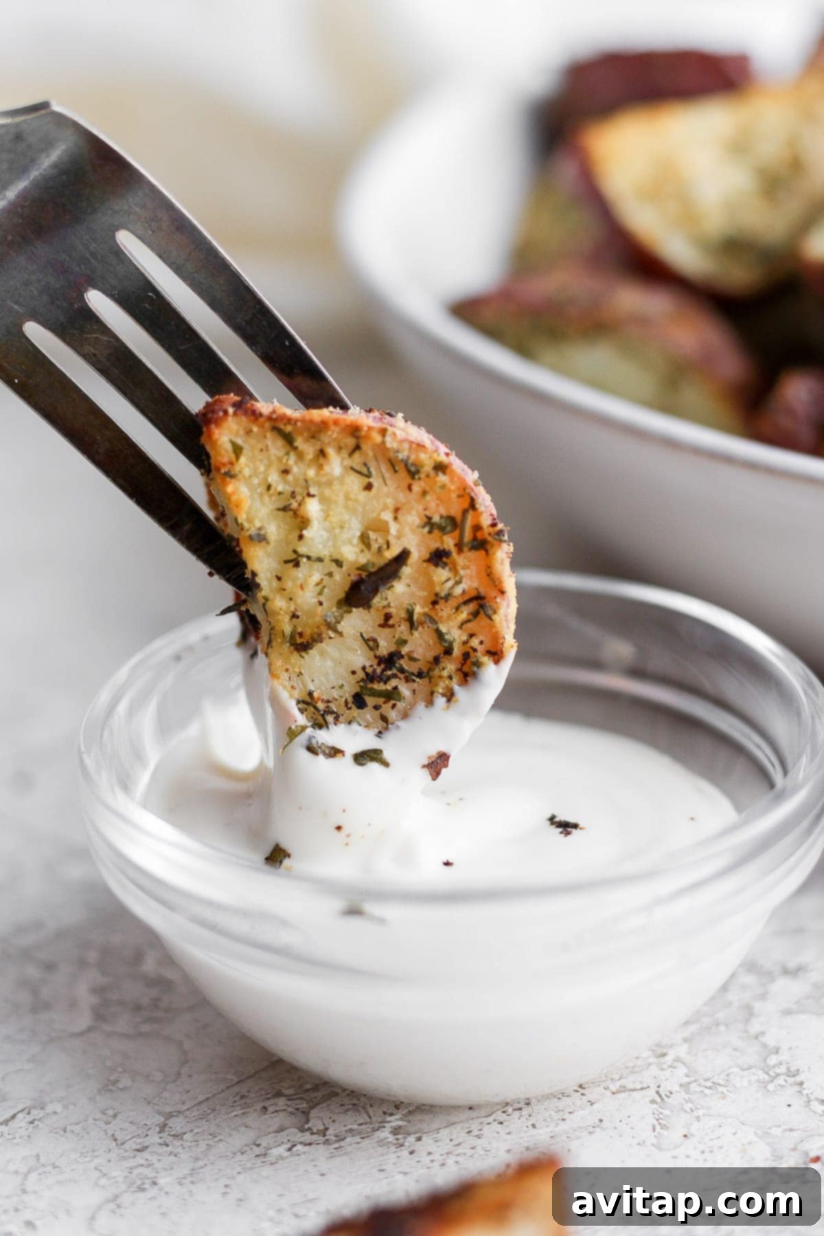 Enjoying a crispy ranch potato with a dip Roasted red potato being dipped into ranch dressing