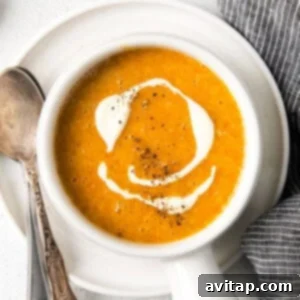 A cozy bowl of creamy butternut squash soup, garnished with a swirl of créme fraîche, depicted for the recipe card.