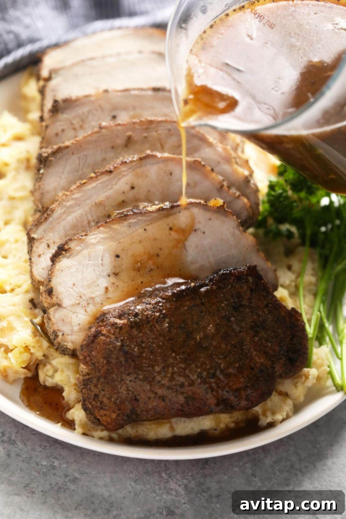 Succulent slow cooker pork loin, perfectly sliced and served on a bed of creamy mashed potatoes, generously topped with savory gravy.