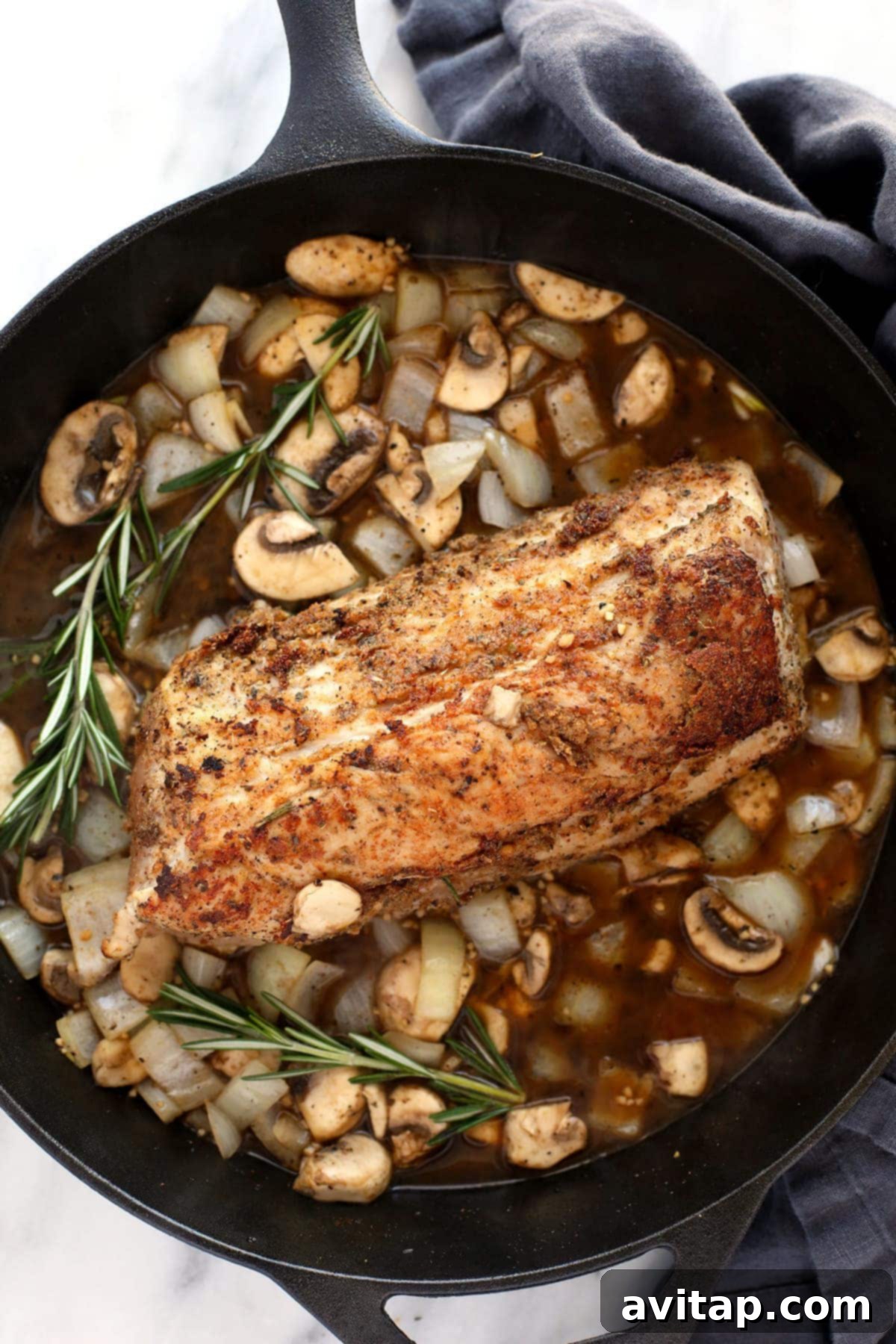 Perfectly cooked pork tenderloin in rich mushroom gravy in a cast iron pan.