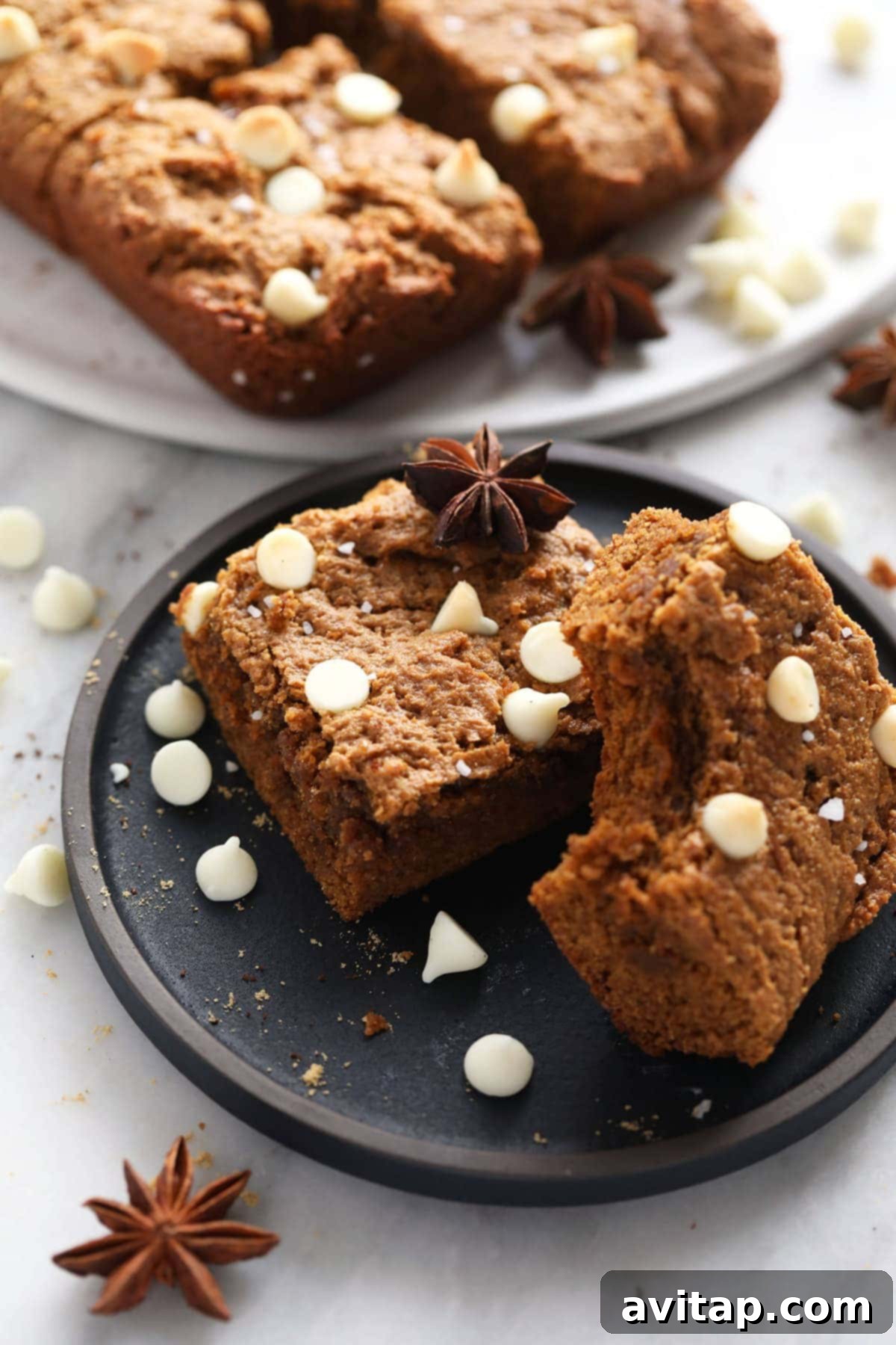 Irresistibly chewy gingerbread cookie bars topped with delicate white chocolate chips, a perfect festive sweet treat.