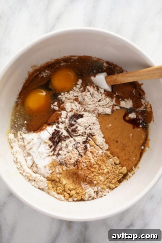 Ingredients for healthy gingerbread cookie bars gathered in a mixing bowl, ready for preparation.