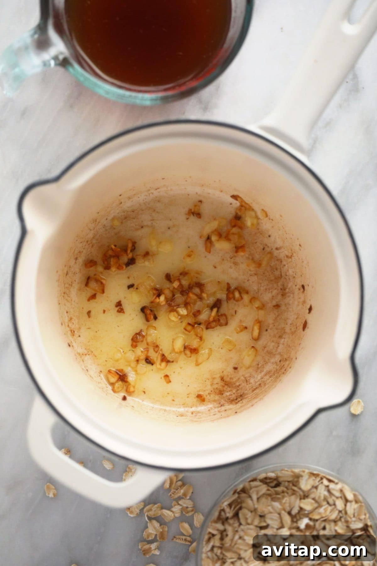 Delicious Savory Oatmeal 4 Finely minced garlic and diced onions gently sizzling in olive oil within a small pot, forming the aromatic and flavorful base for the savory oatmeal.