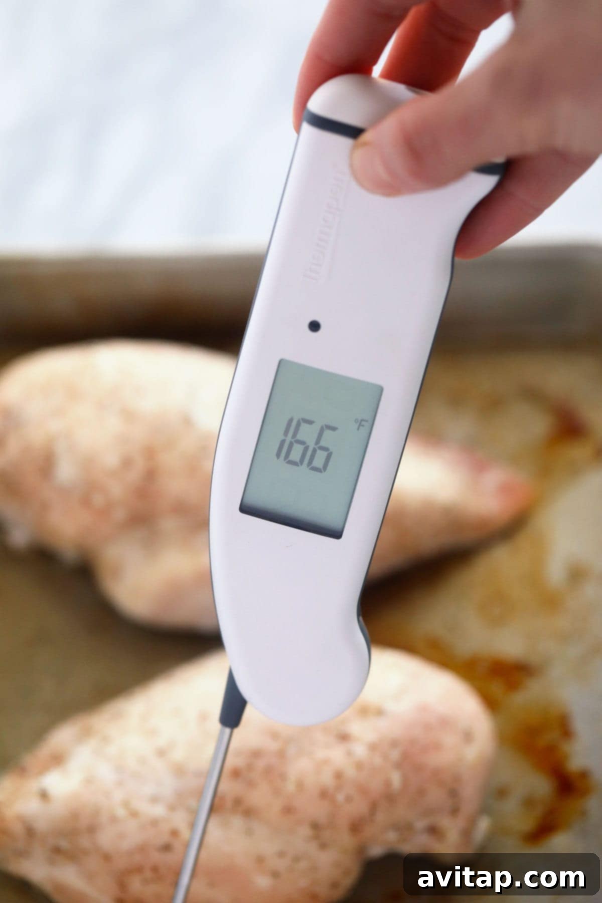 A meat thermometer accurately measuring the internal temperature of a baked chicken breast, ensuring it's cooked to a safe 165ºF.