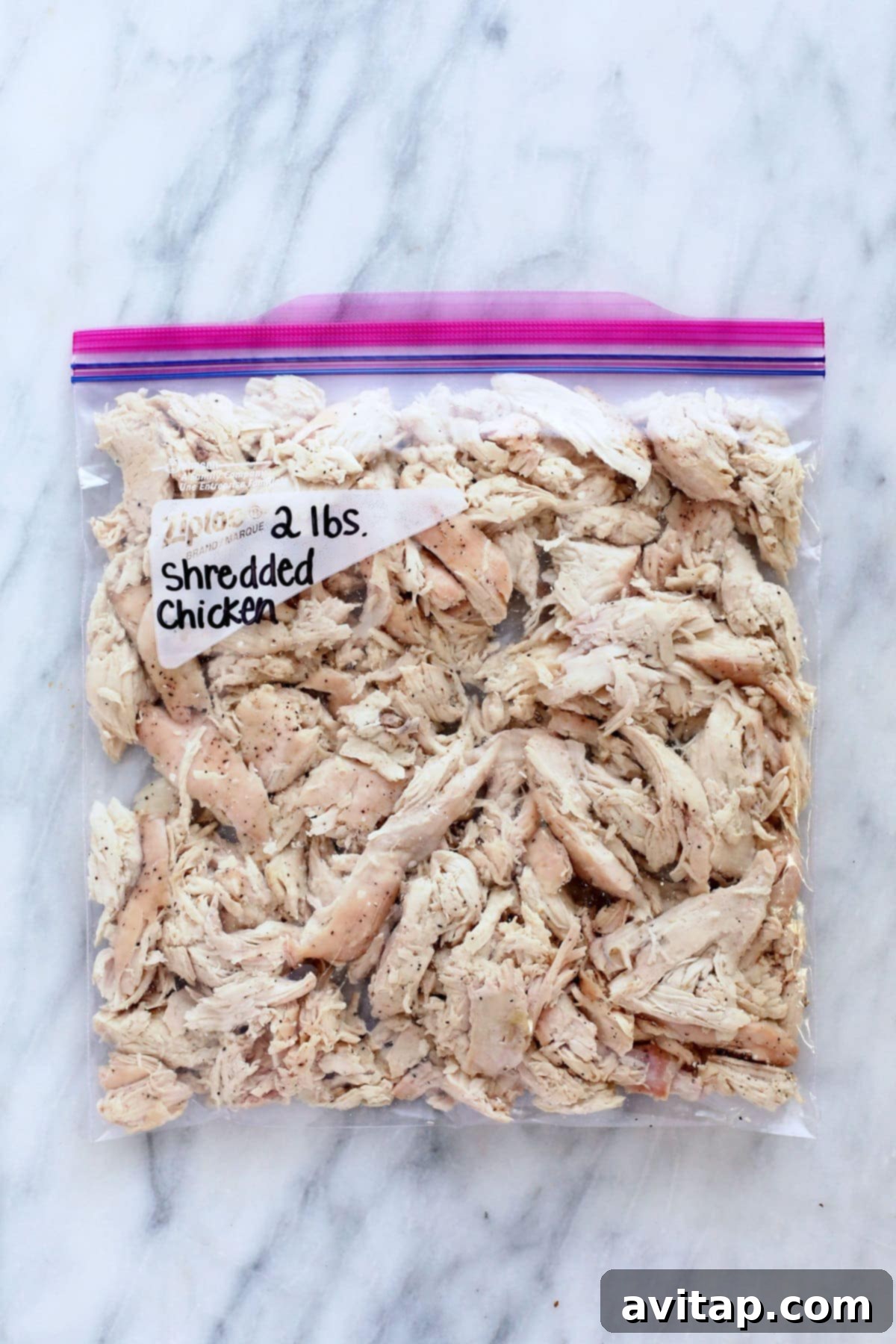 Shredded chicken breast neatly packed in a clear freezer-safe resealable bag, ready for freezing for future meal prep.