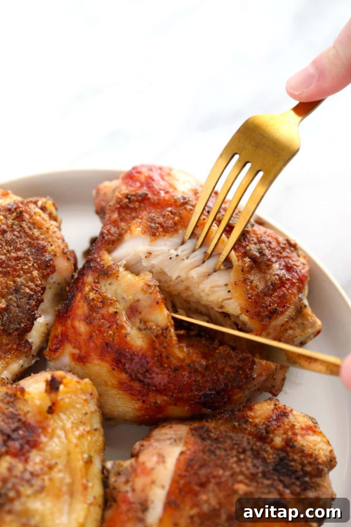 Oven-Fried Crispy Thighs 2 A perfectly cooked, crispy chicken thigh being cut on a plate, ready to be enjoyed.