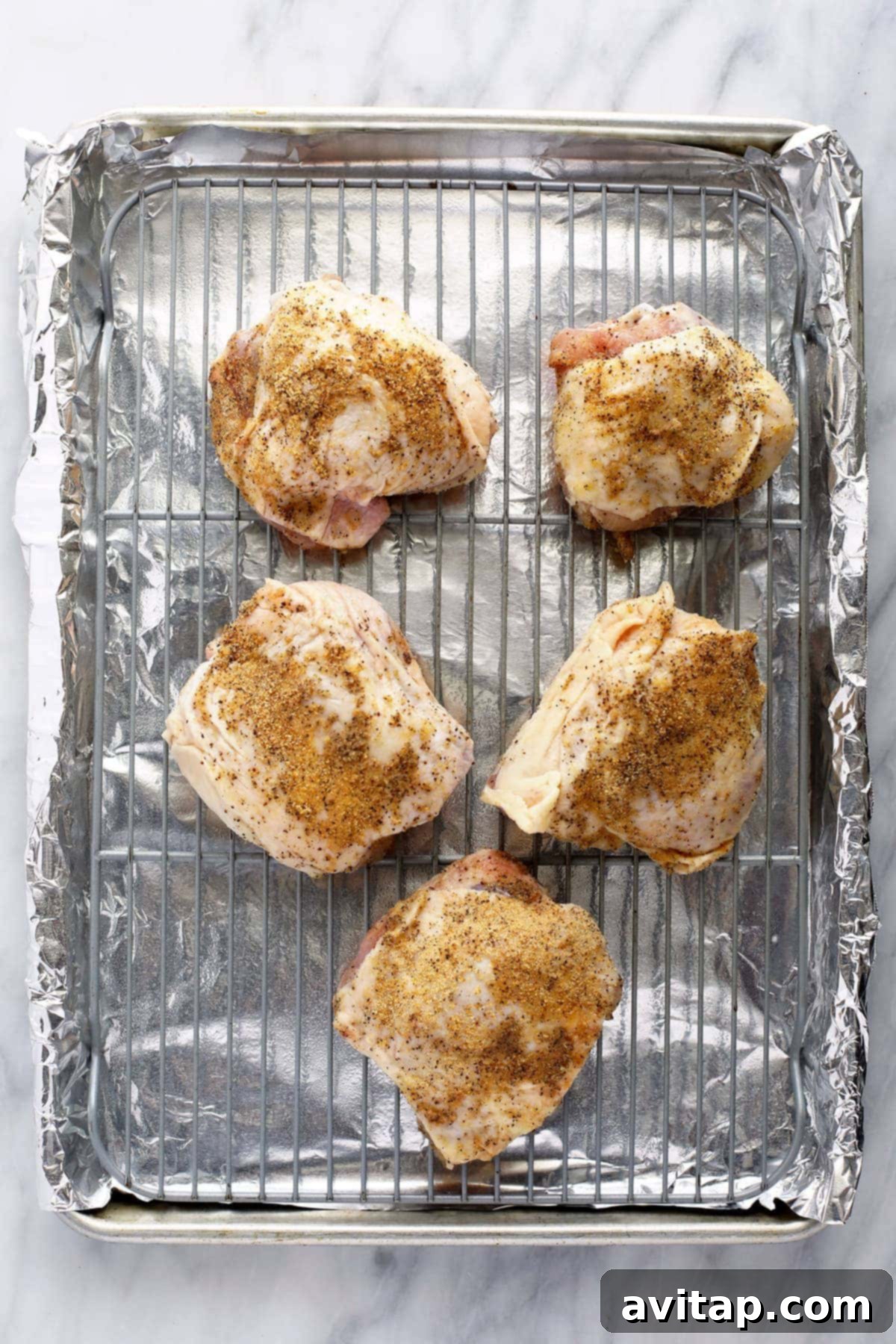 Oven-Fried Crispy Thighs 6 A baking sheet filled with perfectly seasoned raw chicken thighs, ready for the oven.