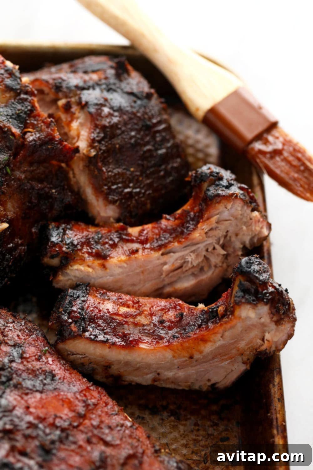 Perfectly cooked sous vide ribs resting on a baking sheet, glistening with sauce.