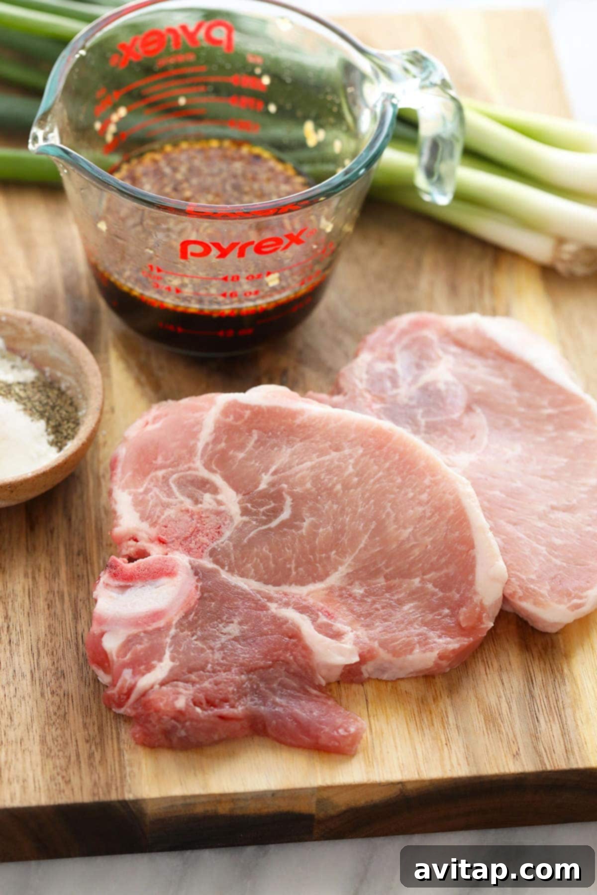 Raw boneless pork chops on a cutting board, ready for our sticky honey pork recipe.