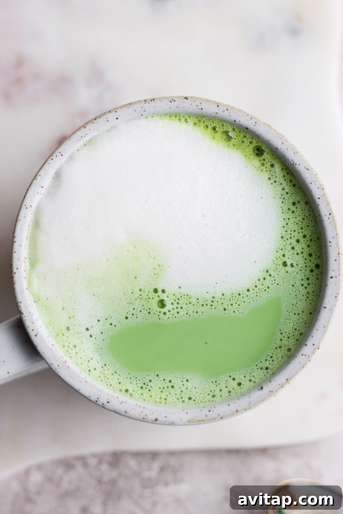 A finished matcha latte in a mug, displaying a perfect blend of green tea and creamy foam, ready to be enjoyed.