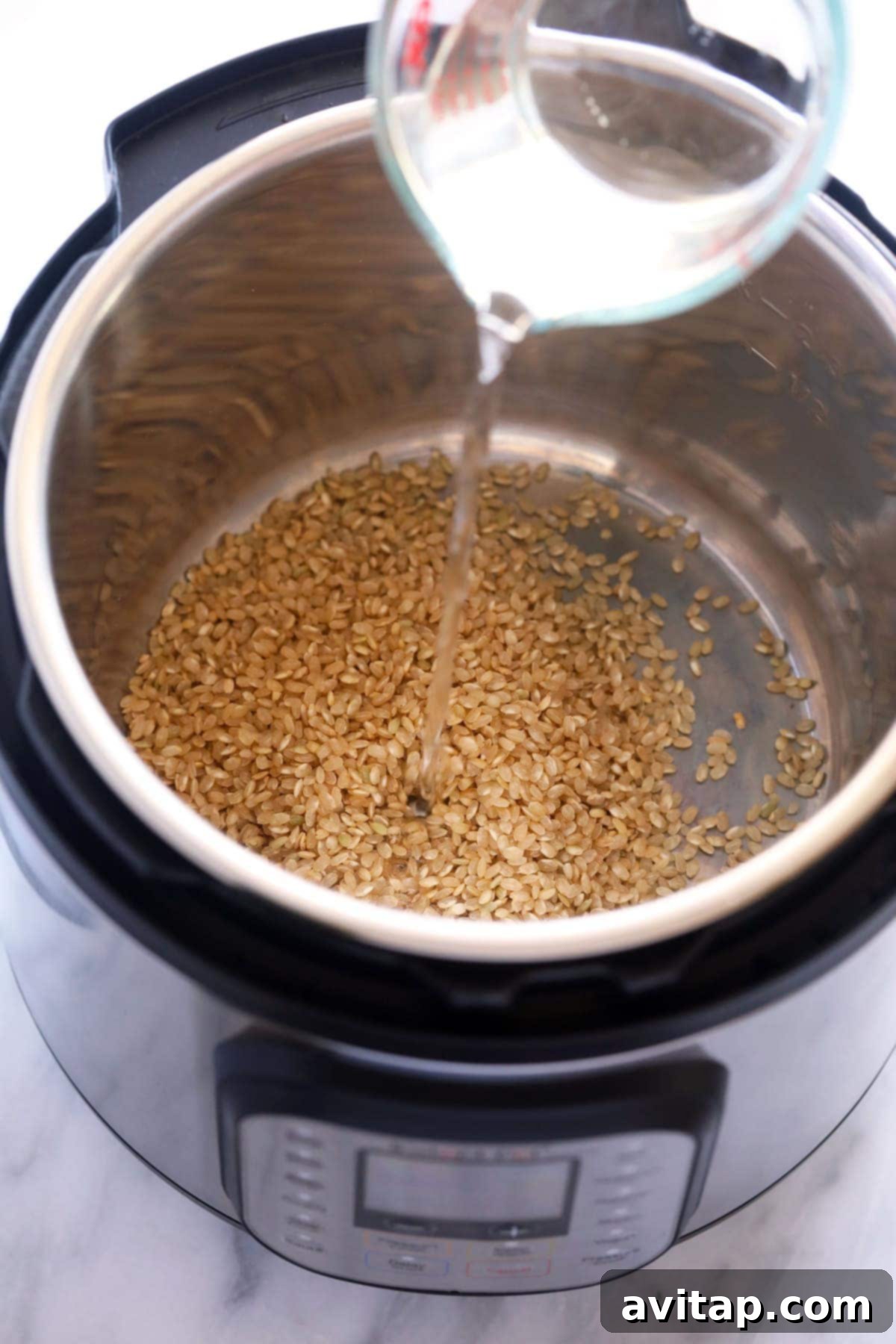 Pouring water into the Instant Pot with brown rice, illustrating the 1:1 ratio for perfect cooking.