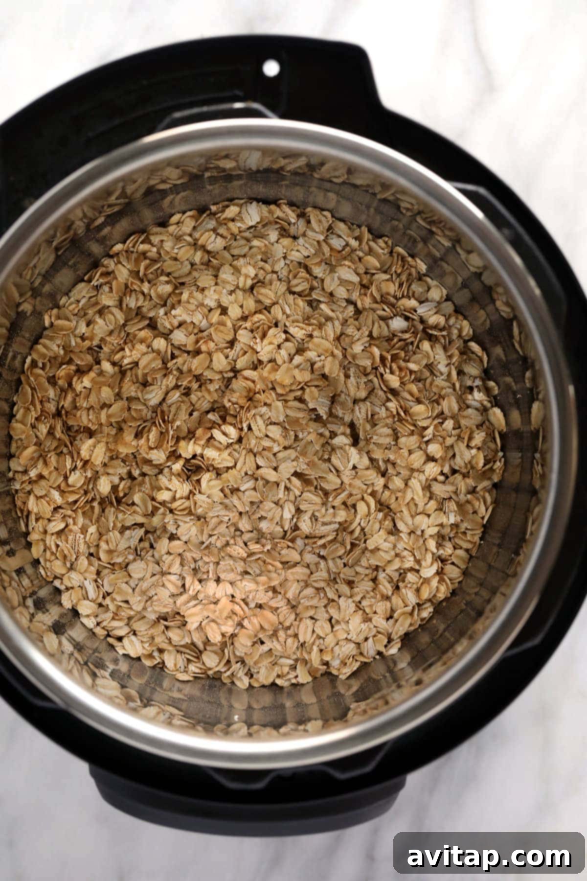 Instant Pot Oatmeal is a healthy breakfast packed with fiber and protein. This Instant Pot Oatmeal recipe is naturally vegan and gluten-free! Close-up of dry rolled oats, almond milk, maple syrup, and a pinch of salt being added to an Instant Pot.