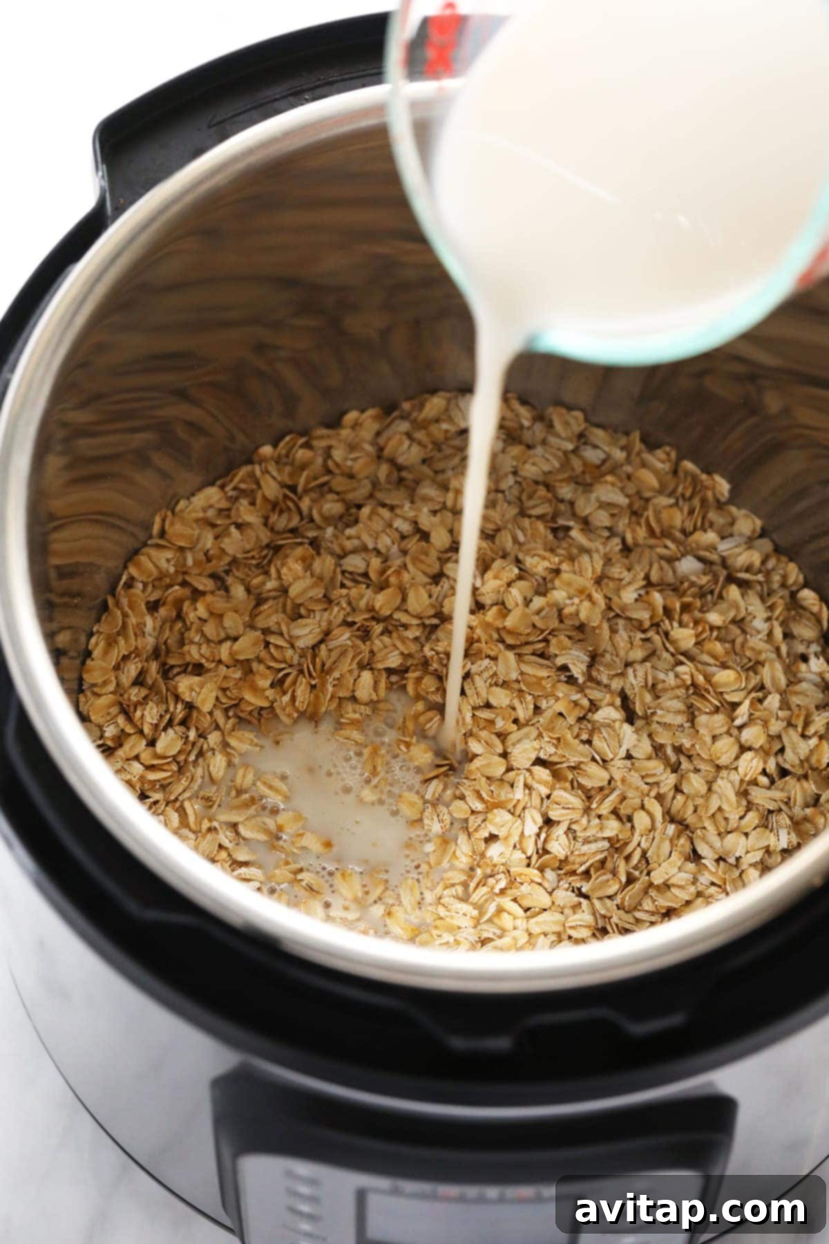 Instant Pot Oatmeal is a healthy breakfast packed with fiber and protein. This Instant Pot Oatmeal recipe is naturally vegan and gluten-free! A stream of almond milk being poured into an Instant Pot containing rolled oats.