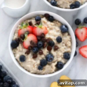 Creamy Instant Pot oatmeal in a white bowl, garnished with fresh berries and a spoon.
