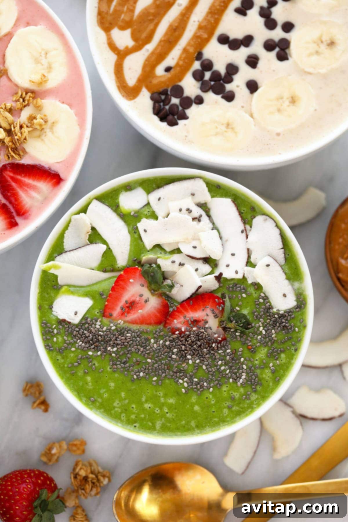 A refreshing green smoothie bowl generously garnished with fresh strawberries, shredded coconut, and nutrient-rich chia seeds.