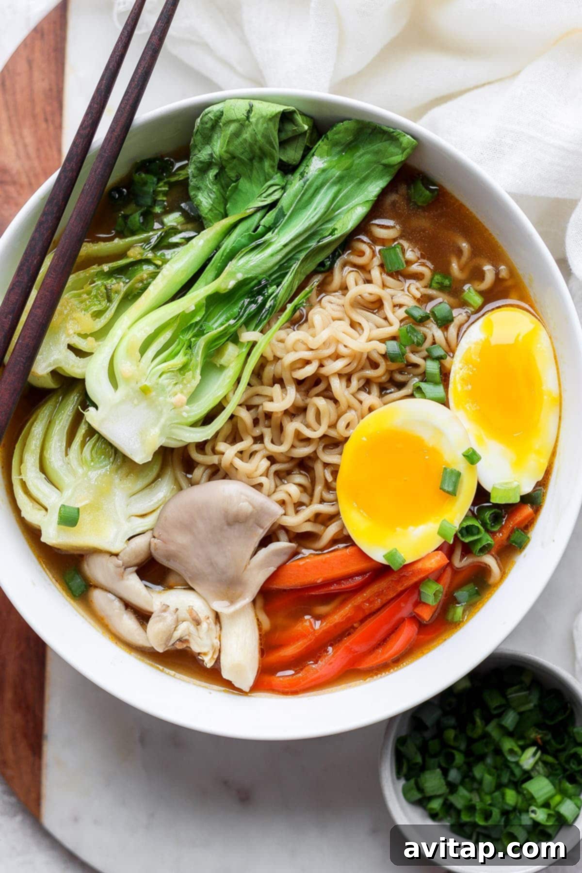 A generous bowl of vegetarian ramen, garnished with soft-boiled eggs and a medley of fresh, vibrant vegetables.