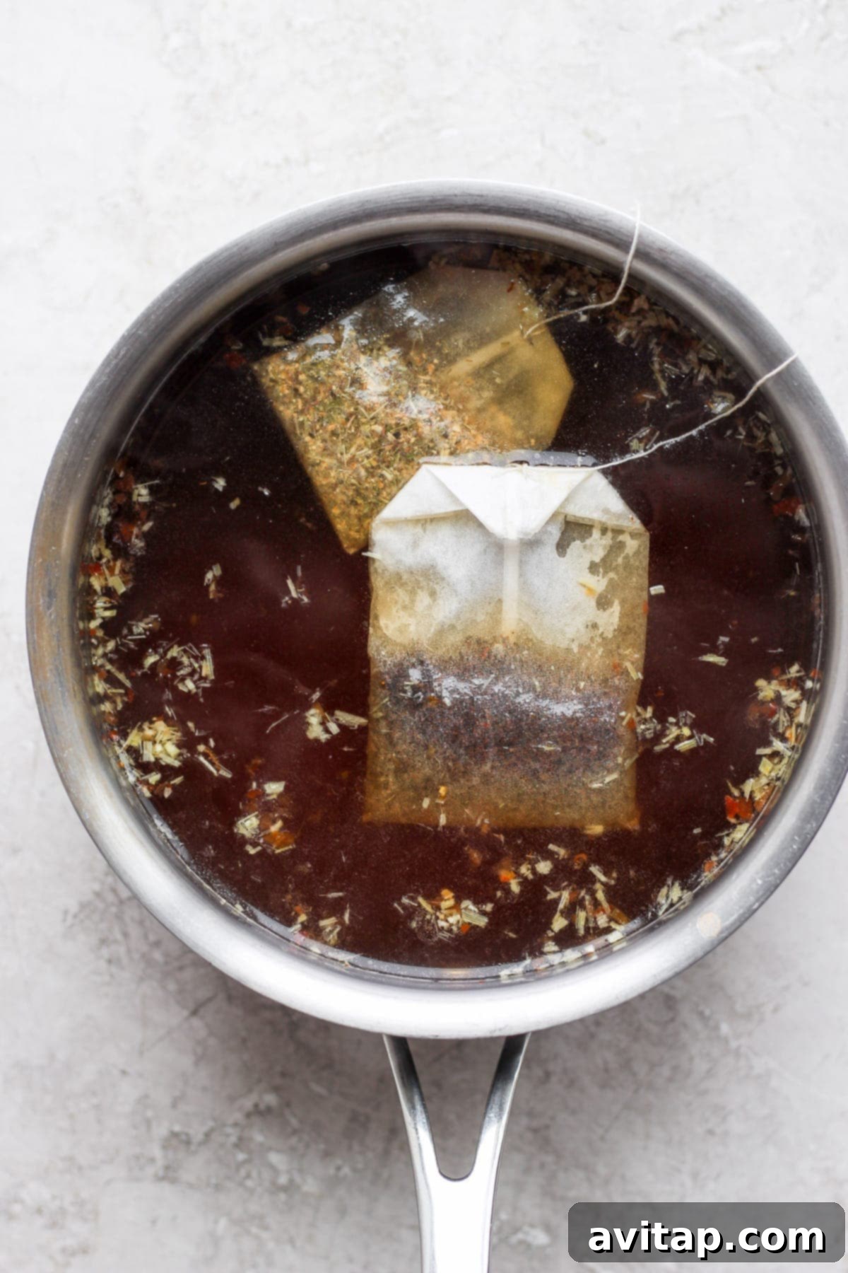The black tea and ginger marinade mixture steeping in a saucepan, with tea bags visible, ready for eggs.