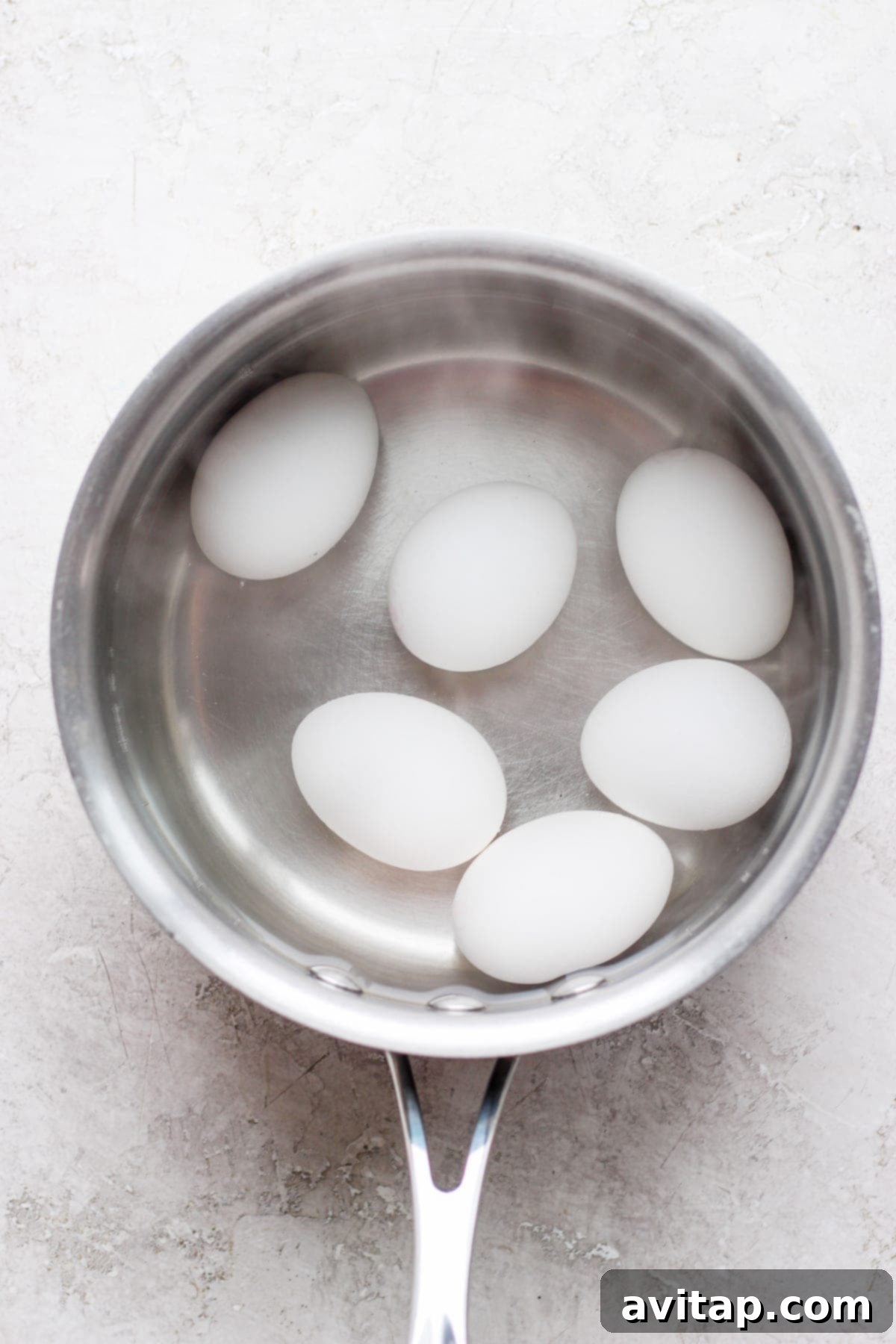 Large eggs gently boiling in a saucepan of water, preparing for their transformation into ramen eggs.