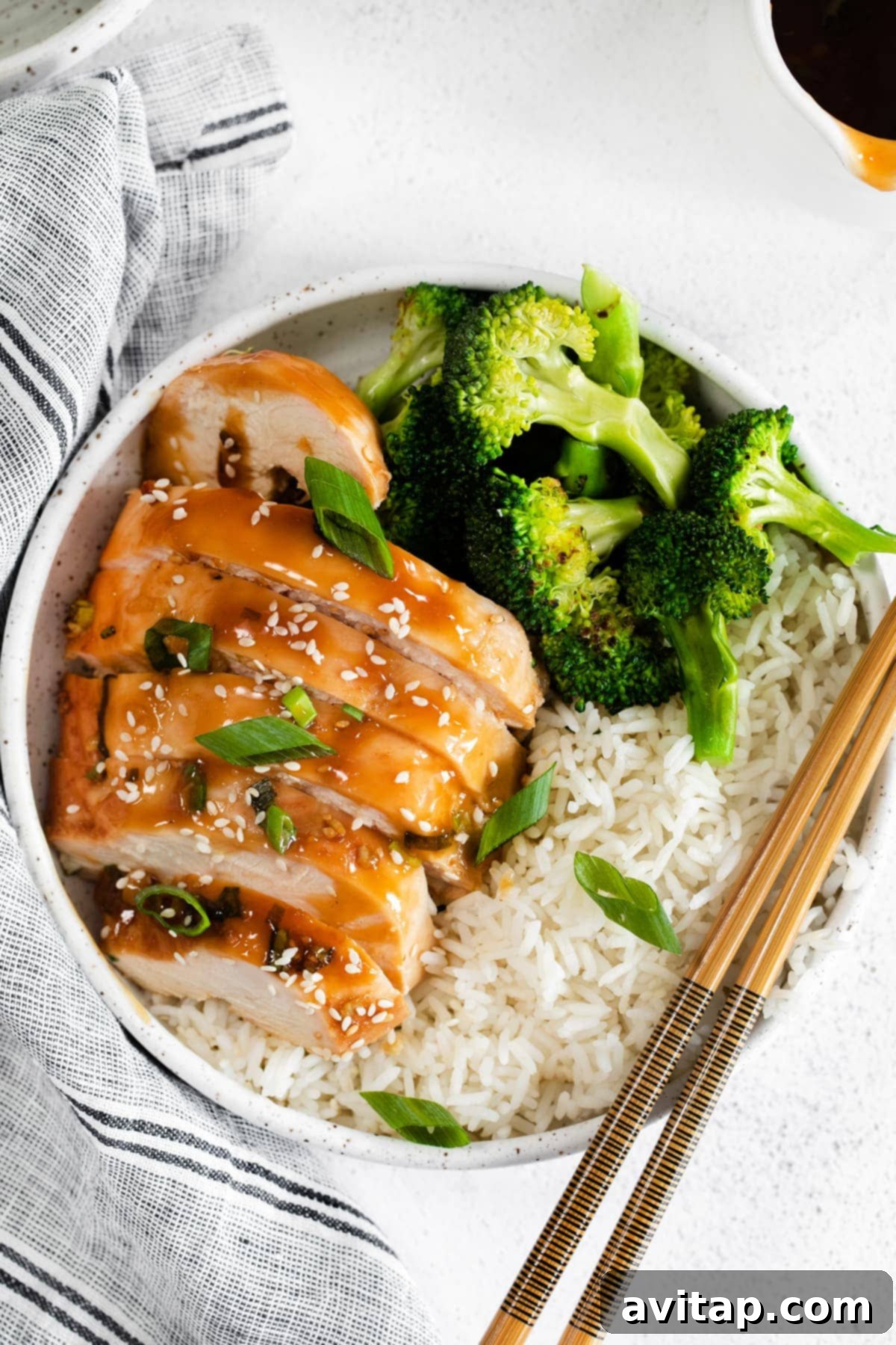 Sliced baked teriyaki chicken breast served with steamed broccoli and fluffy white rice, showcasing a perfectly glazed and tender meal