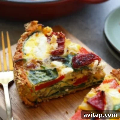A perfectly baked slice of sweet potato crust quiche, showcasing its vibrant layers of eggs, vegetables, and creamy goat cheese, all encased in a unique and healthy sweet potato crust, ready on a rustic cutting board.