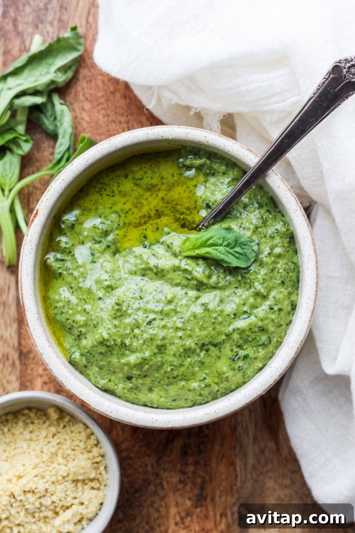 Vegan pesto is light, fresh, and 100% plant-based. It comes together with fresh basil, lemon, olive oil, garlic, and vegan parmesan cheese! Freshly made vegan pesto in a bowl with a spoon, ready to be served