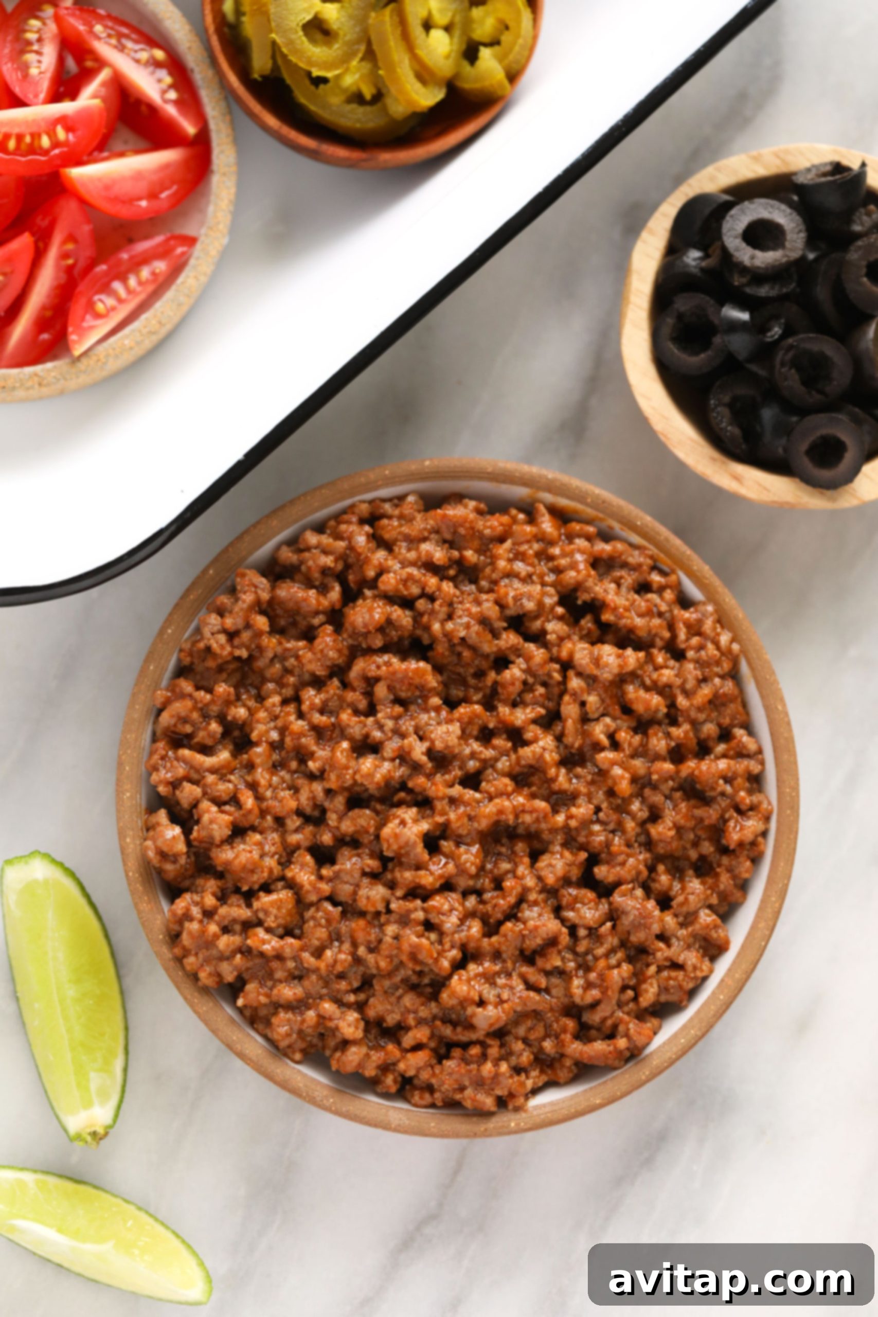 Flavorful beef taco meat, the foundation of perfect nachos. A bowl of freshly cooked and seasoned beef taco meat, ready to be layered onto crunchy tortilla chips for nachos.