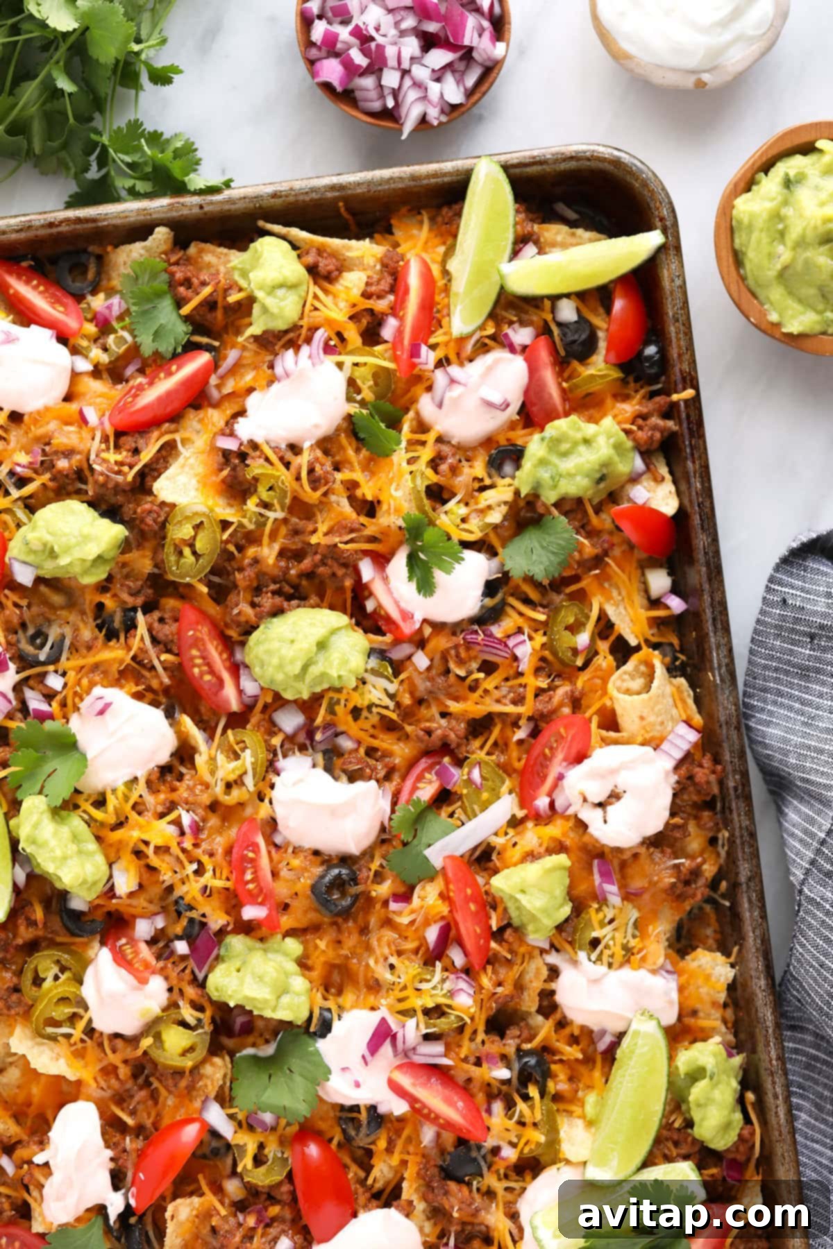 Baked ground beef nachos with perfectly melted cheese. A sheet pan of ground beef nachos fresh out of the oven, with melted cheese and ready for fresh toppings.