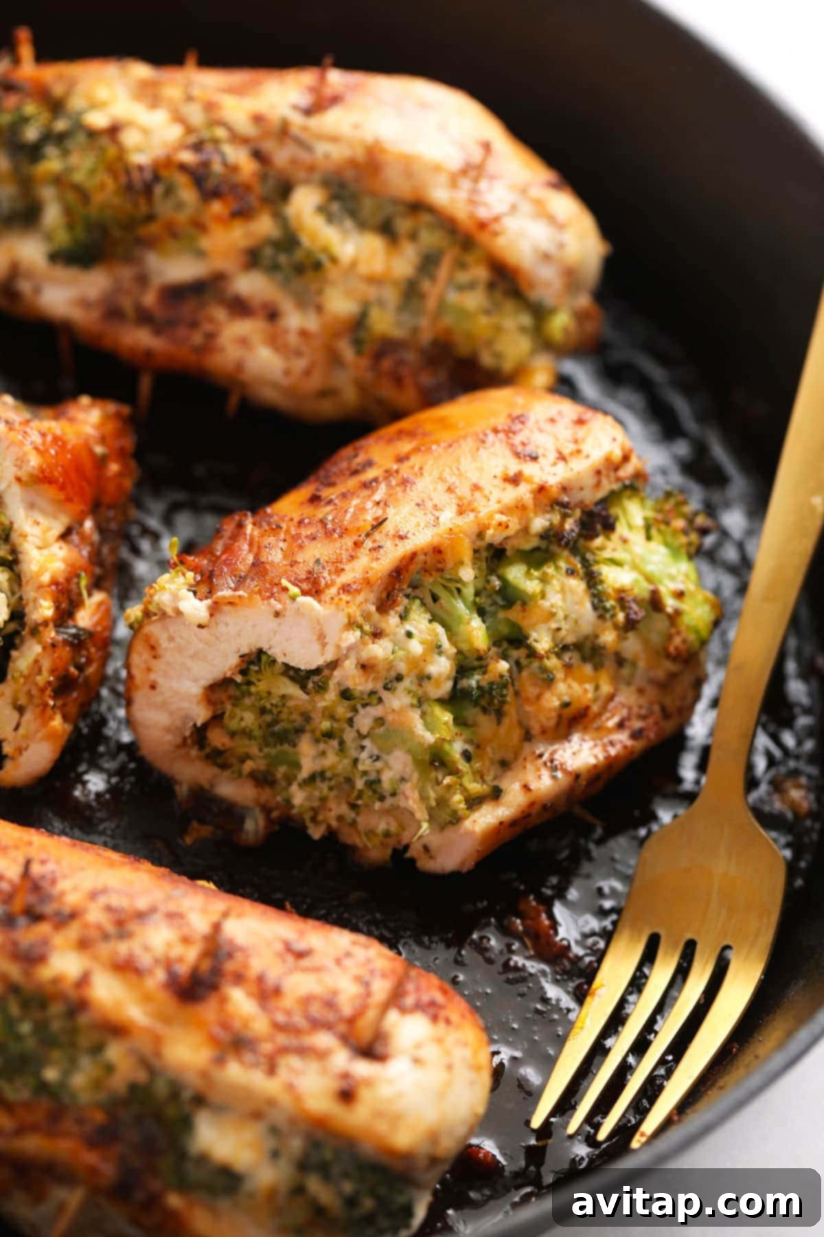 Broccoli and cheese stuffed chicken breast in a cast iron skillet, golden brown and perfectly cooked.