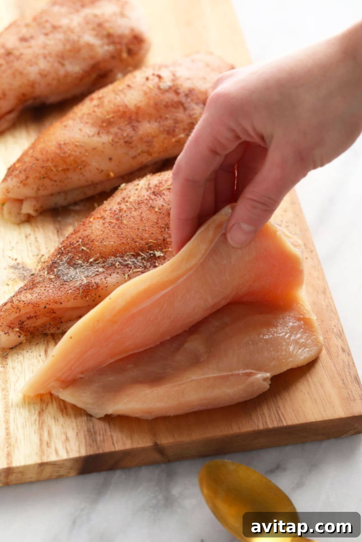 Raw chicken breast cut open, ready to be generously stuffed with broccoli and cheese filling.