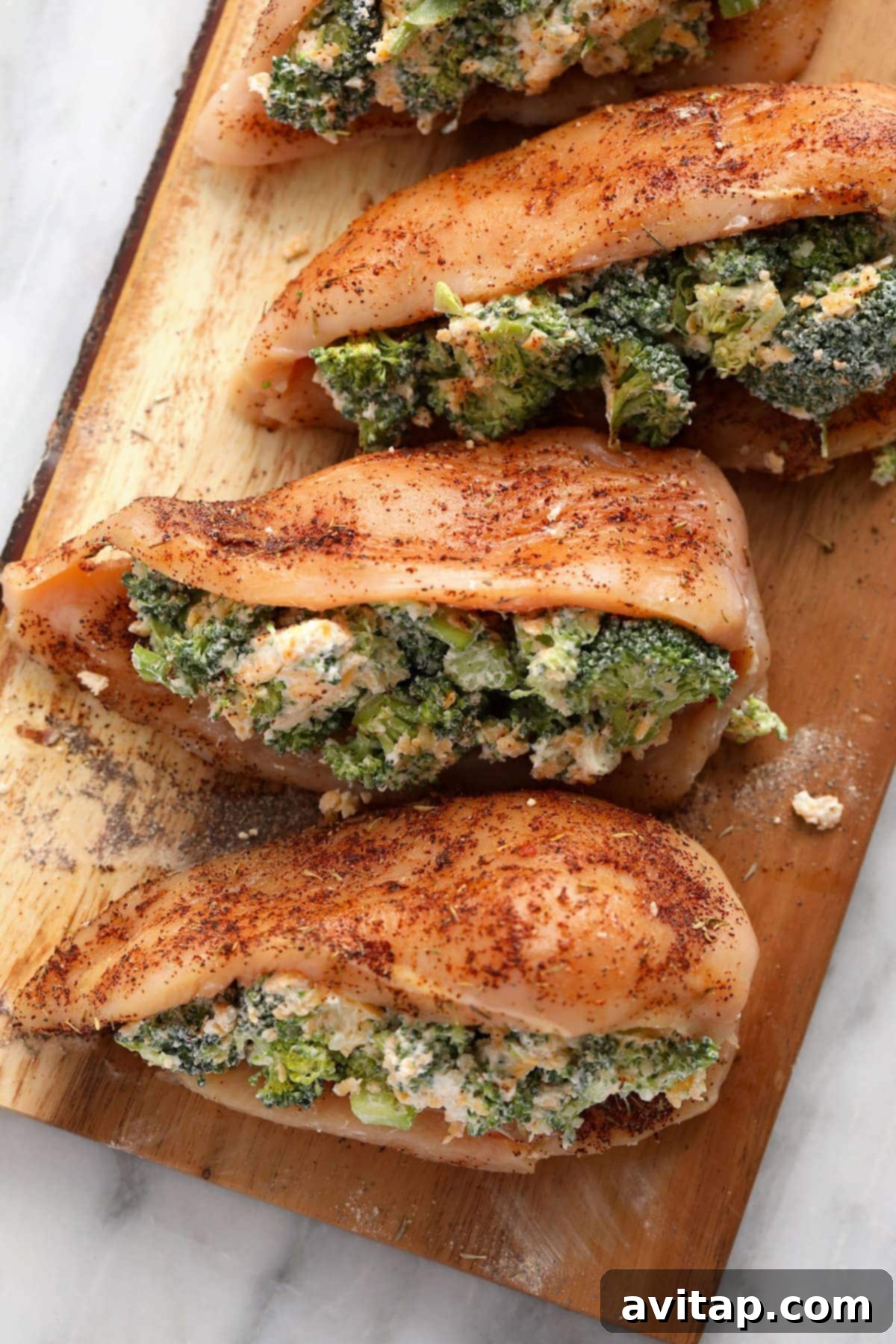 Raw broccoli and cheese stuffed chicken breasts in a cast iron skillet, ready to be seared and then baked.