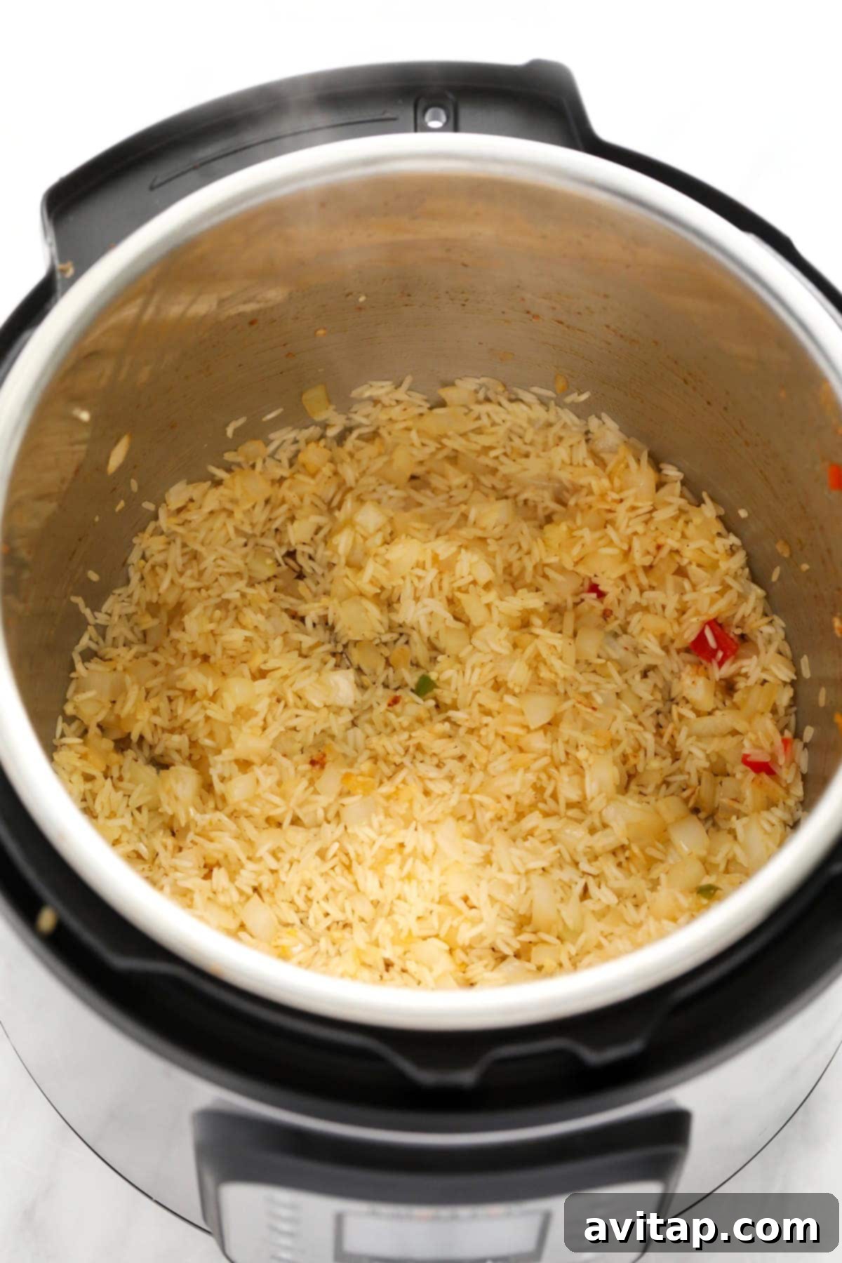Quick Instant Pot Burrito Bowls 4 Uncooked long grain rice and onions toasting in the Instant Pot, preparing a flavorful base for burrito bowls