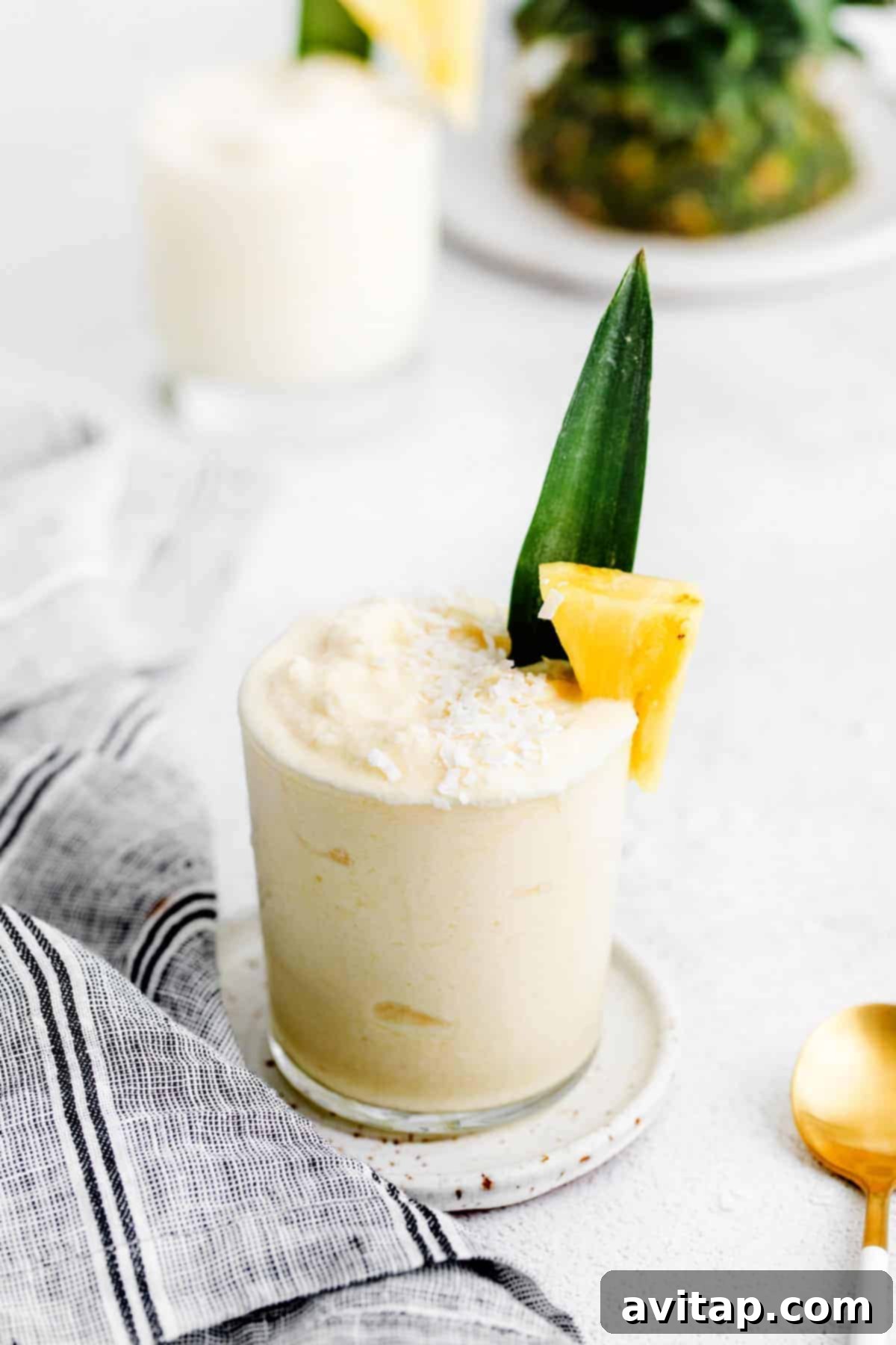 Refreshing piña colada cocktail in a glass, garnished with a fresh pineapple chunk and vibrant green leaf, perfect for a summer day.