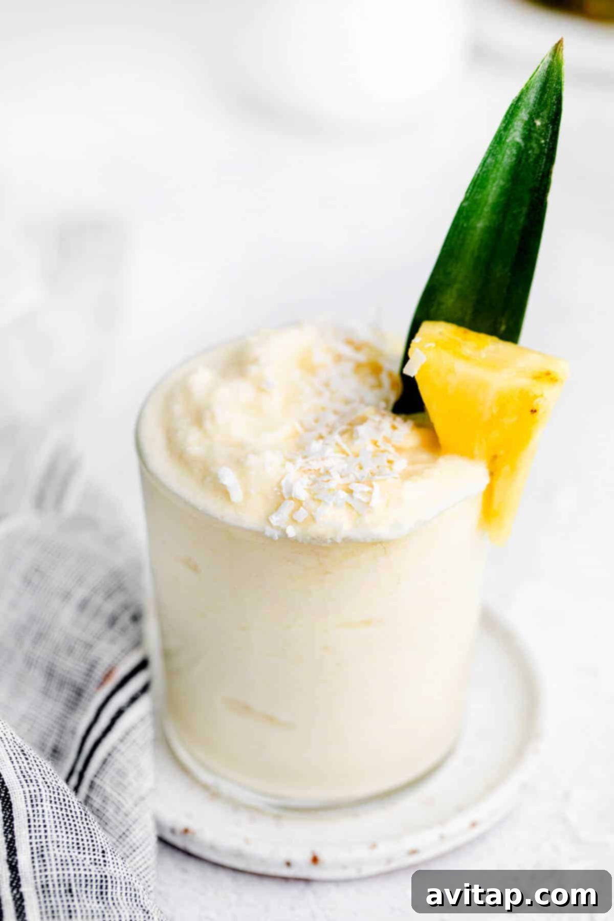 A beautifully blended piña colada in a stemmed glass, adorned with a fresh pineapple wedge, perfectly chilled and ready to enjoy.