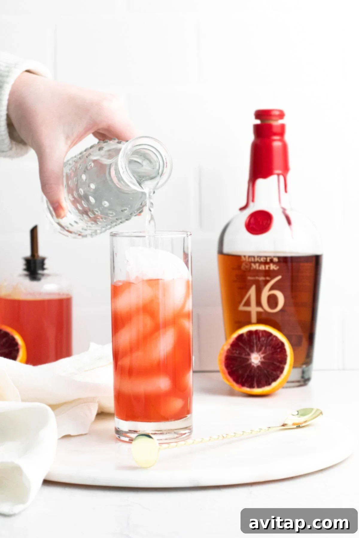 Sanguine Sunset Sip 8 A close-up shot of a Blood Orange Smash being stirred in a highball glass.