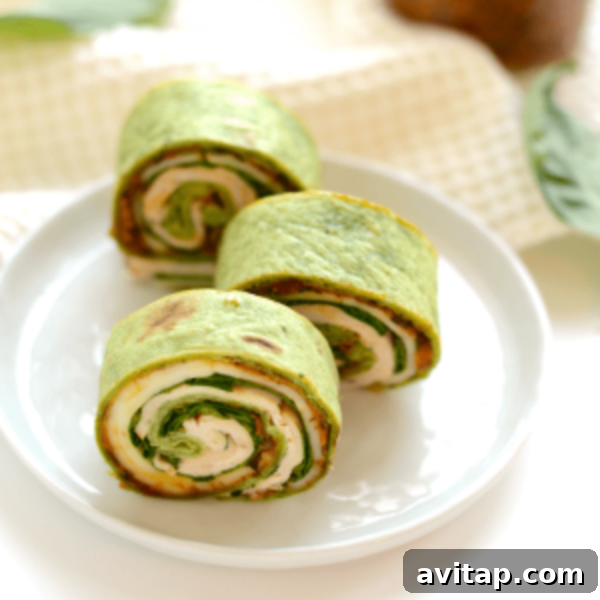 Three spinach and chicken wraps on a plate.