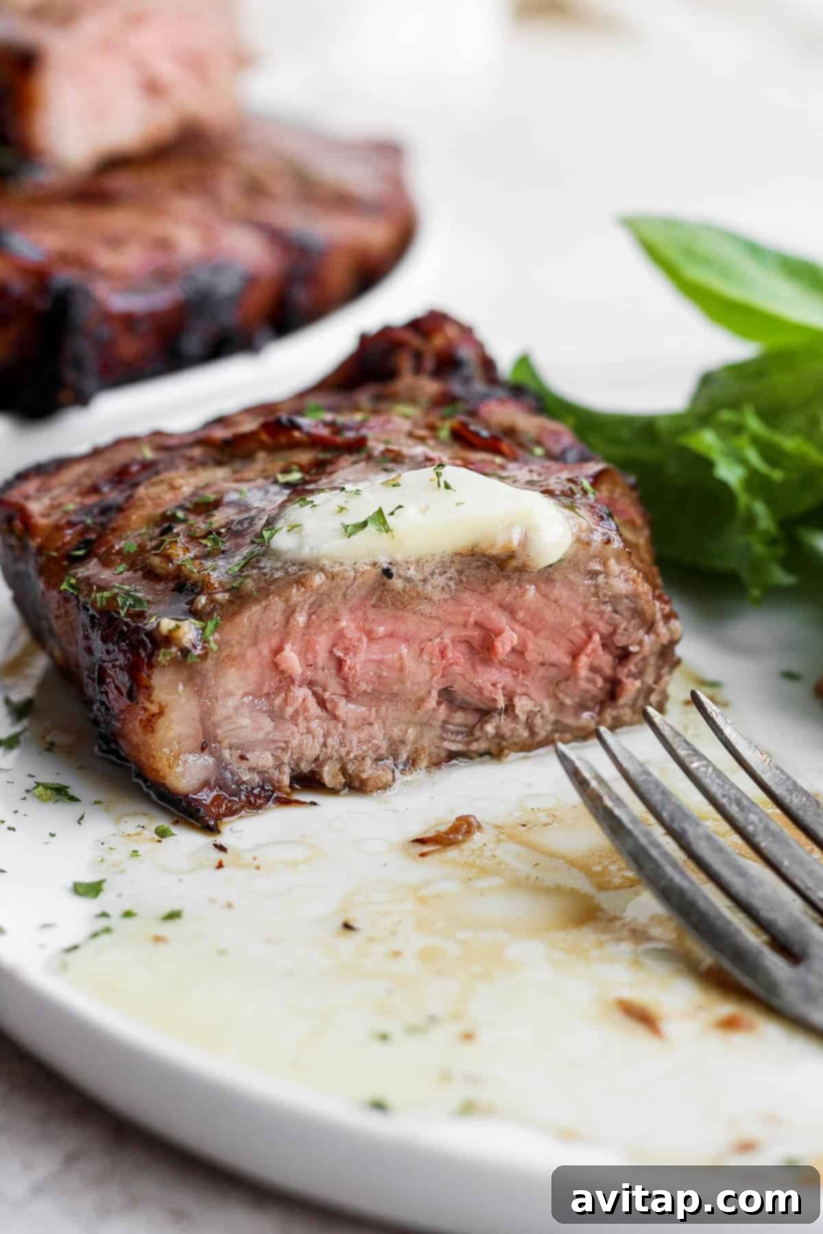 A grilled steak, perfectly sliced to reveal its medium-rare interior, topped with a pat of melting butter.