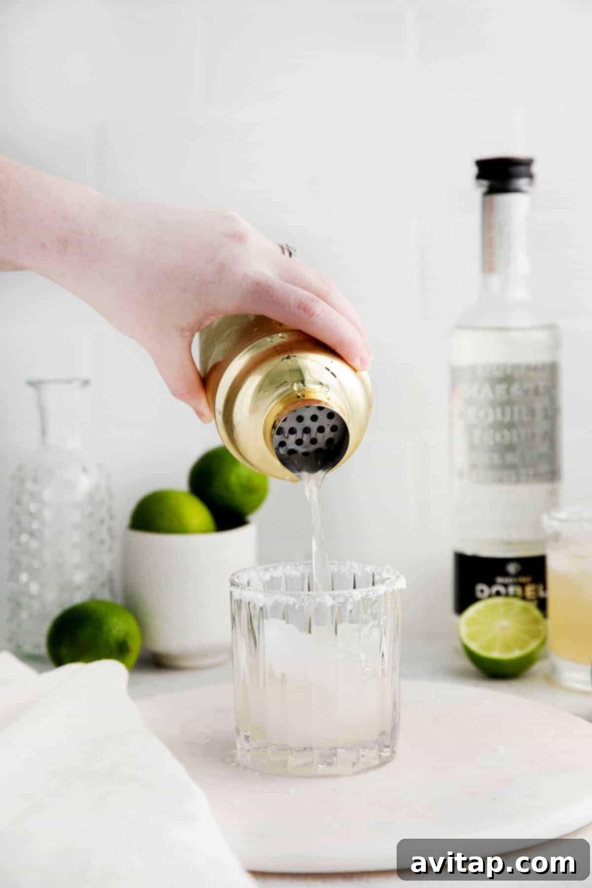 The Perfect Margarita 7 Pouring the margarita into a cocktail glass with lime.