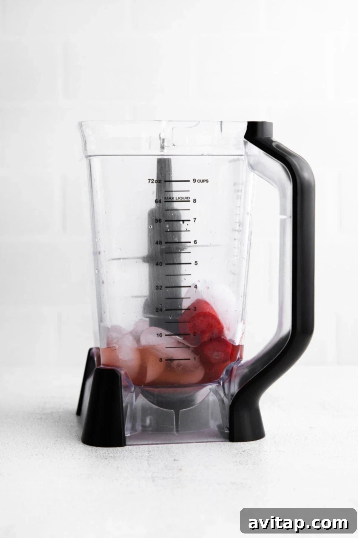 Frozen strawberries being added into a high-speed blender, ready to be blended into a margarita
