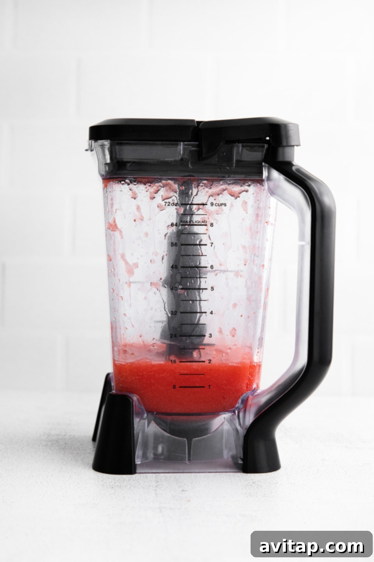 A vibrant red frozen strawberry margarita, perfectly blended and still in the high-speed blender container