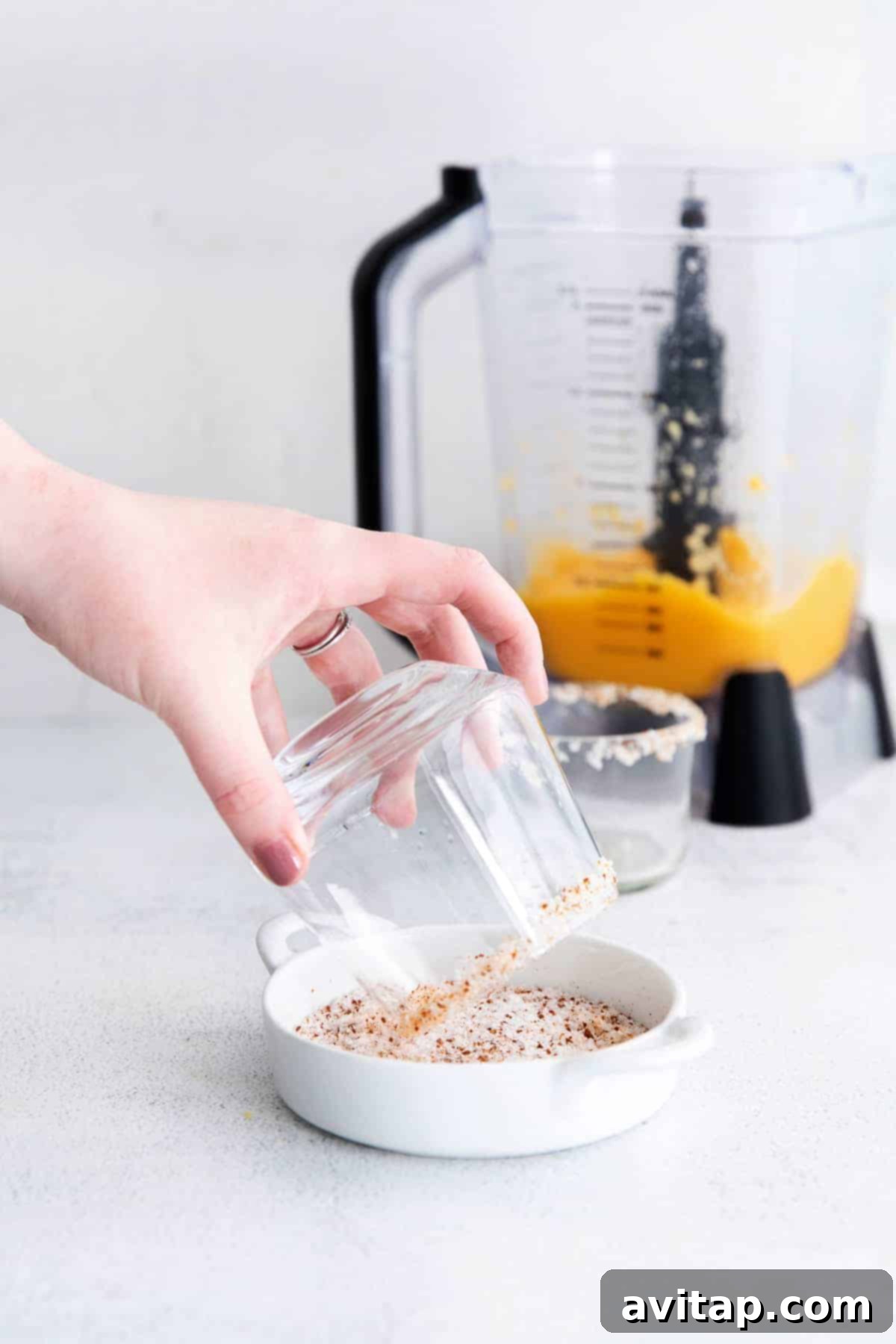 Sun-Drenched Mango Margarita 7 A hand carefully moistening and salting the rim of a margarita glass, demonstrating the preparation process.