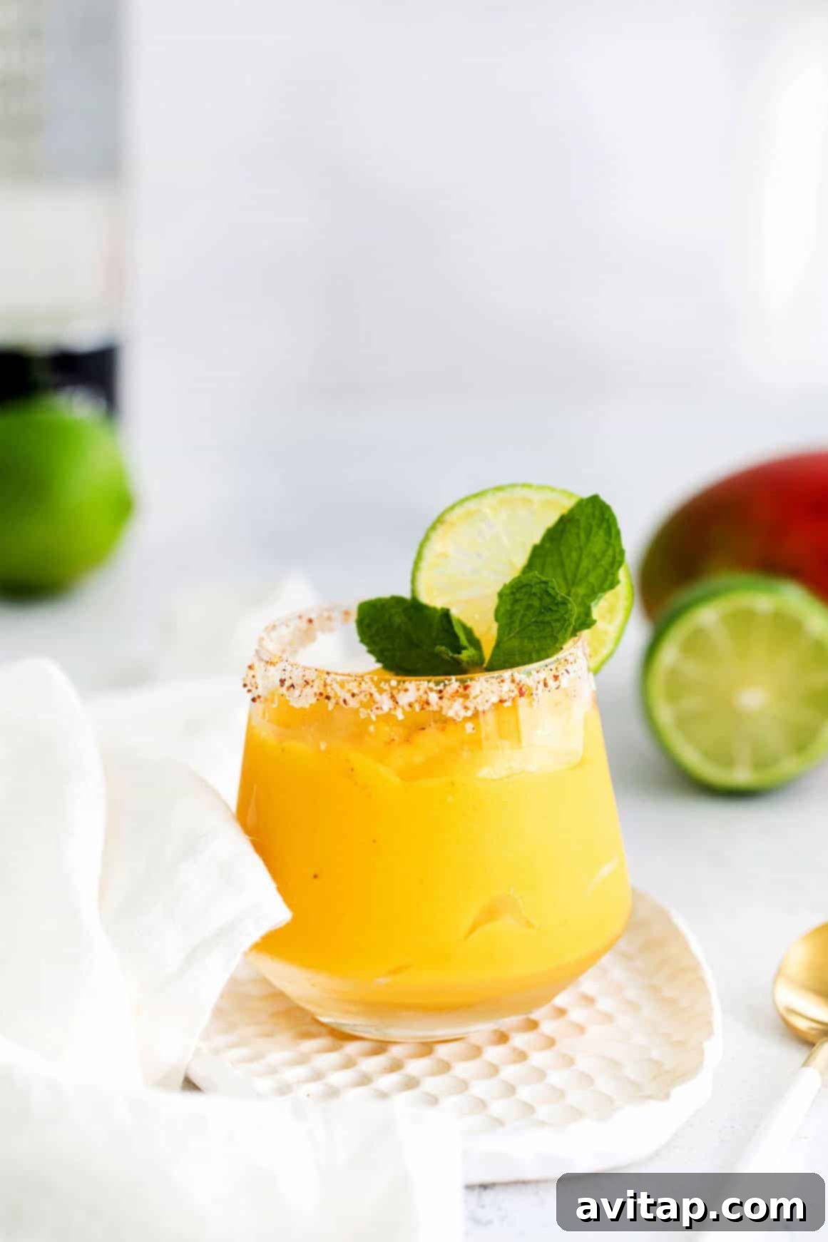 Sun-Drenched Mango Margarita 8 A perfectly blended mango margarita in a tall glass, garnished elegantly with fresh mint leaves and a lime wedge, ready to be served.