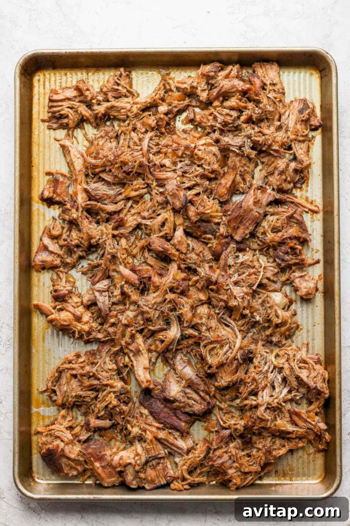 Close-up of crispy carnitas on a baking sheet after broiling.